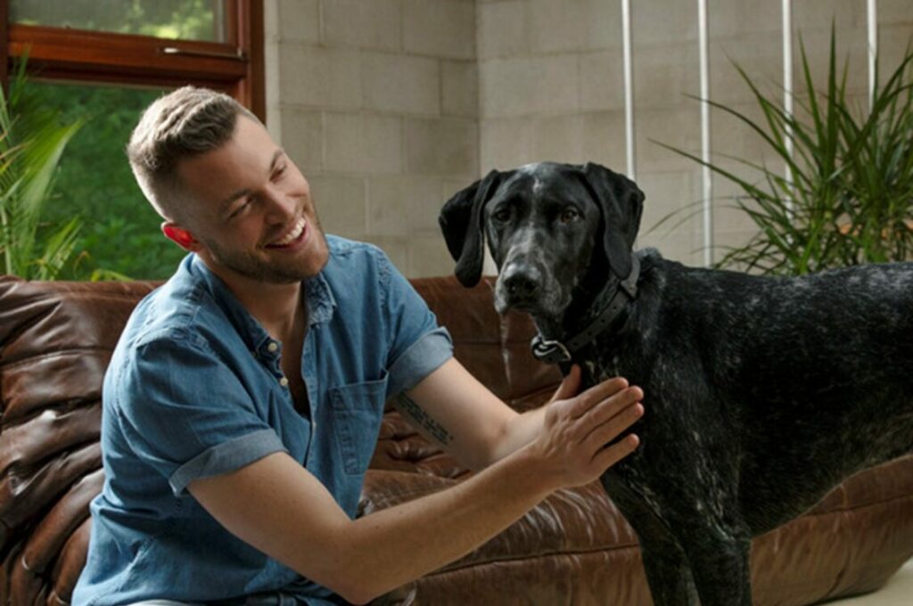 A man petting his dog in the living room at home.