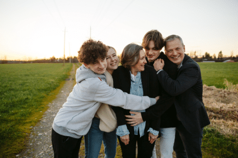 They are laughing and close enjoying evening sunset in field together.