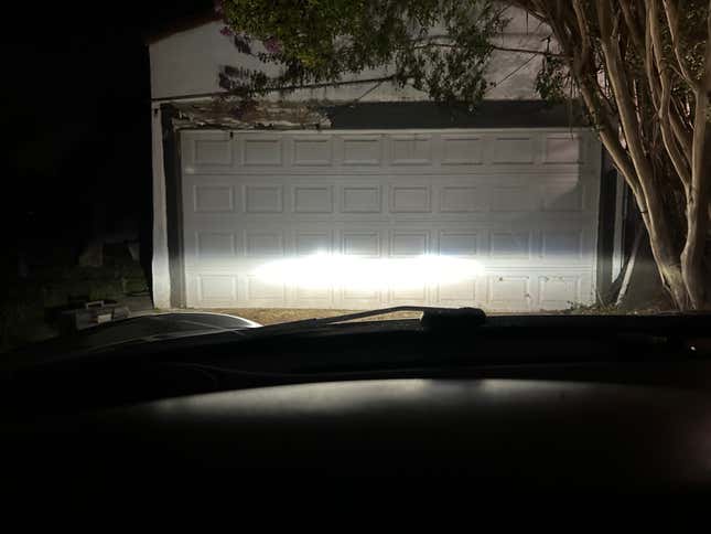 A bright headlight beam pattern is projected on a garage door.