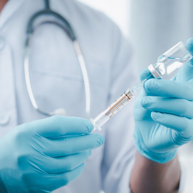 A medical worker preparing a COVID-19 vaccine dose for delivery.