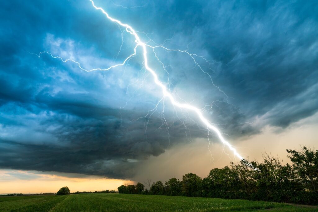 dramatic lightning thundertbolt bolt strike in daylight rural surrounding bad weather dark sky