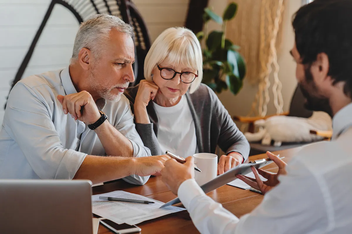 Financial advisor explaining paperwork to elderly retired couple front of desk