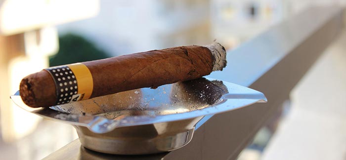 Image of lit cigar in ashtray for Quotacy blog Do Cigars Affect Life Insurance Rates?