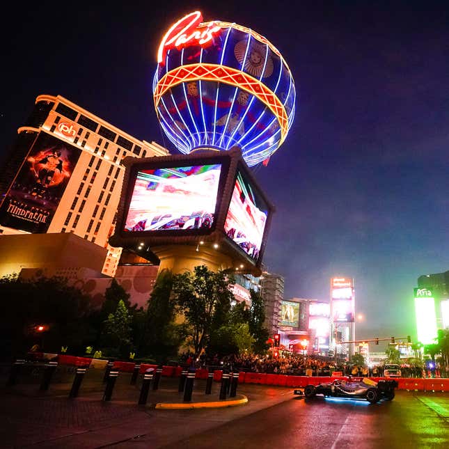 A photo of a Formula 1 car driving past a Las Vegas casino. 