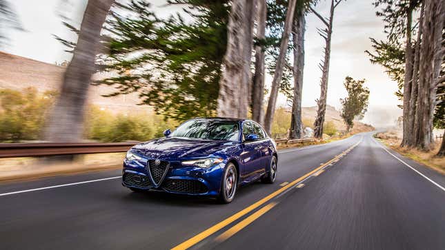 A photo of a blue Alfa Romeo Giulia driving on a highway. 