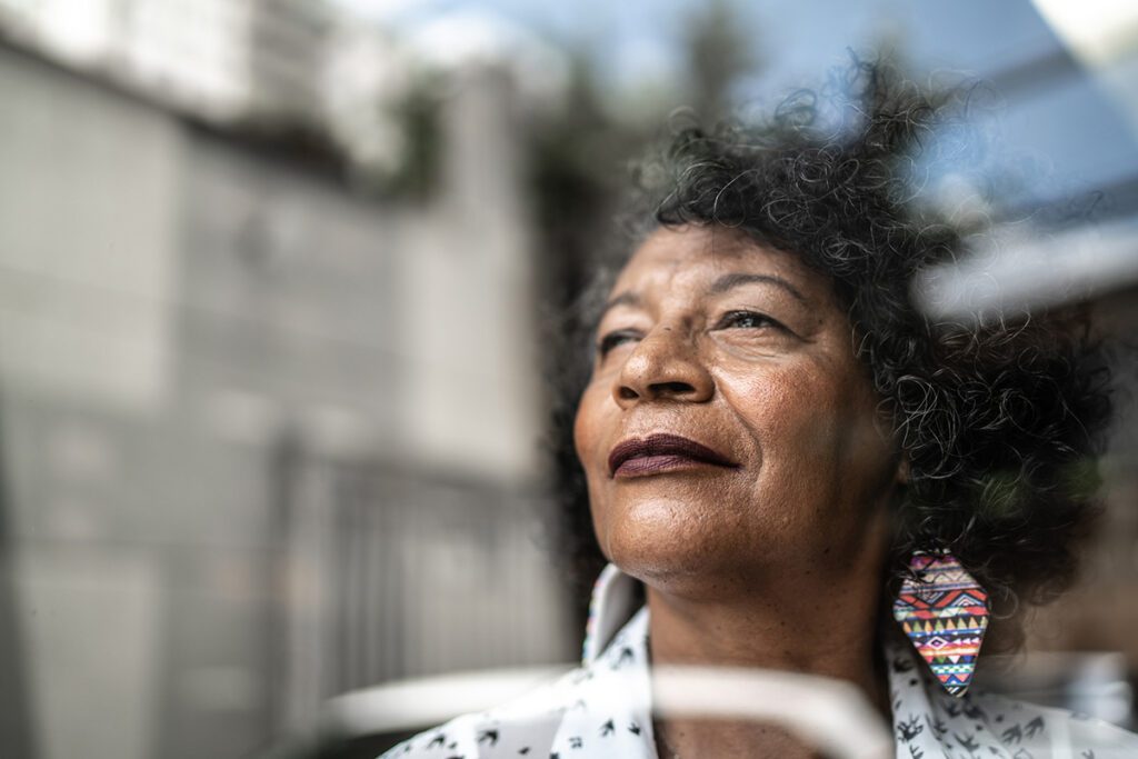 An older woman looks out the window, contemplating the fact that she's quit smoking