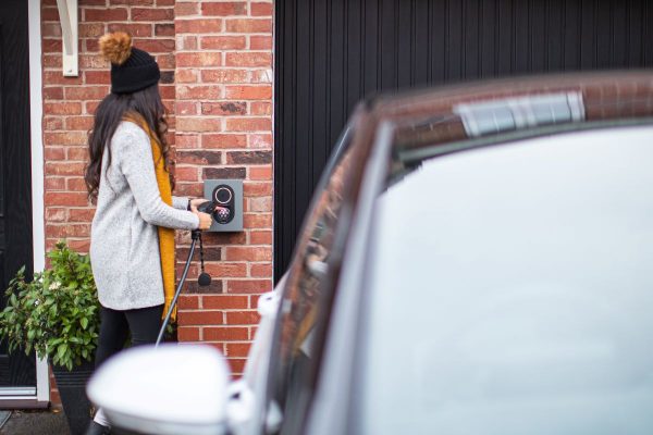 Woman plugging electric vehicle into wall socket