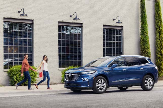 A blue Buick Enclave with a man and woman holding hands walking up to it.