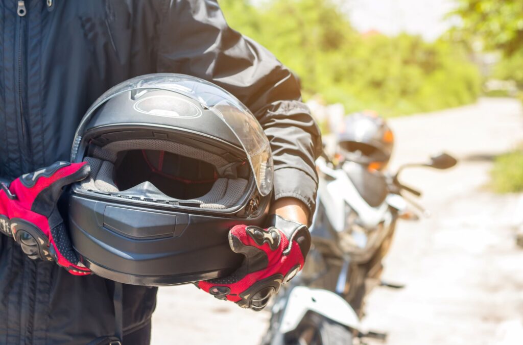 Person holding their motorcycle helmet with gloves on