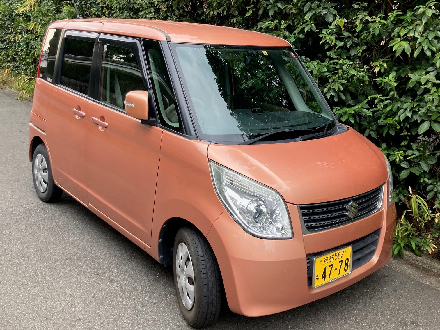 A Suzuki Palette kei car parked by a hedge in Japan