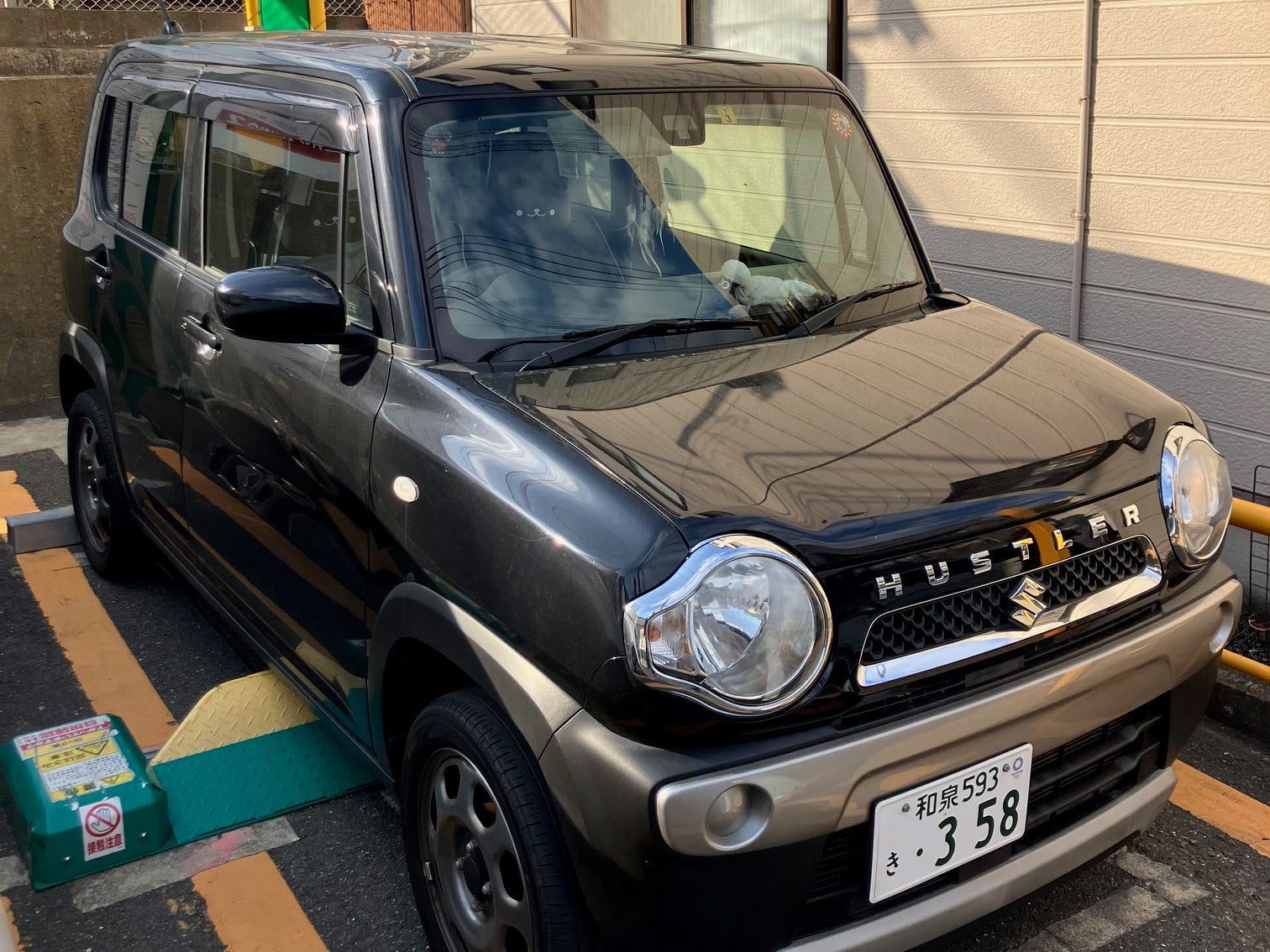 A Suzuki Hustler parked in a small driveway in Japan