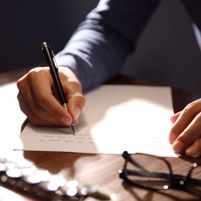 A person writing a letter