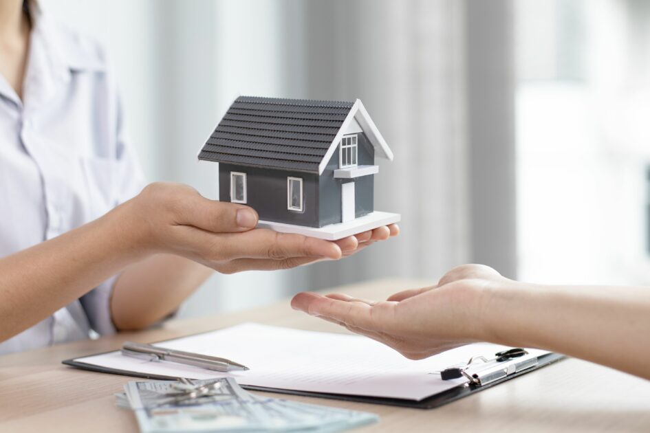Does Homeowners Insurance Cover Wear and Tear? Image of someone holding a small house and handing it to someone, GasanMamo