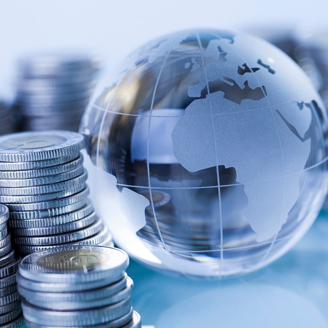 A Lucite globe with coins stacked next to it