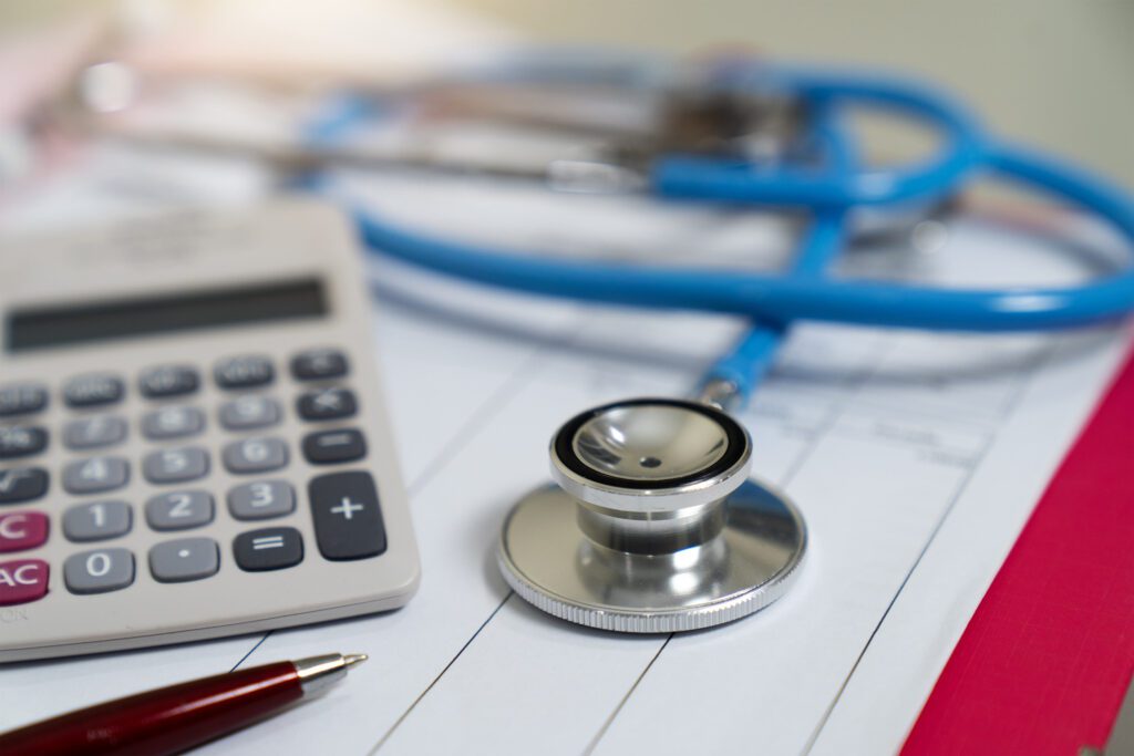 A photo of a stethoscope and calculator arranged on a table.