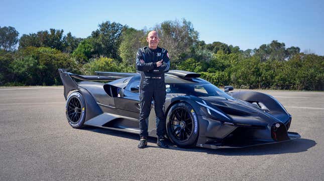 Front 3/4 view of a Bugatti Bolide with Andy Wallace posing with it