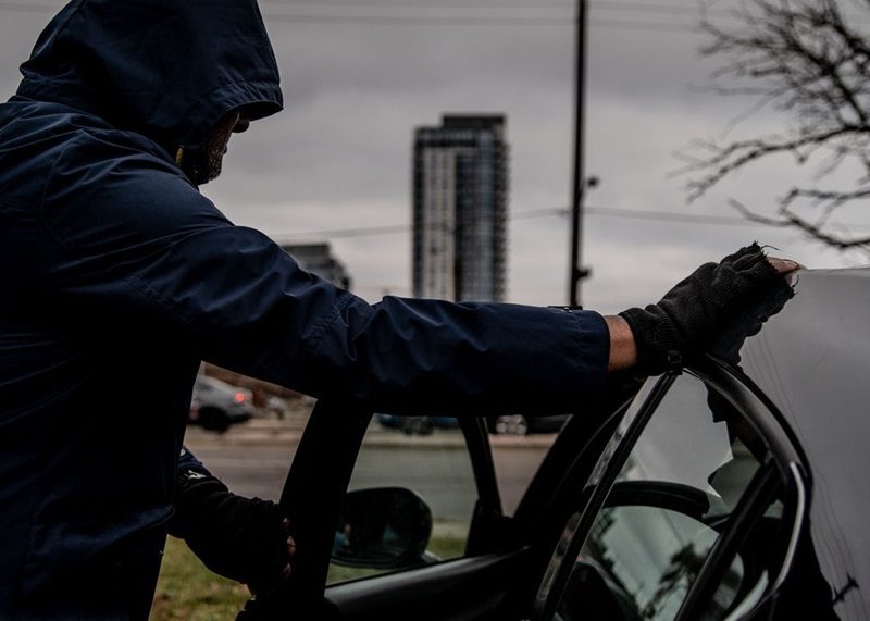 A thief attempting to break into a car