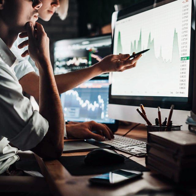 Businesspeople pointing at stock charts on a computer