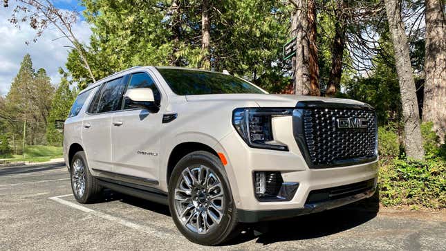 A front 3/4 shot of the GMC Yukon parked in front of some trees