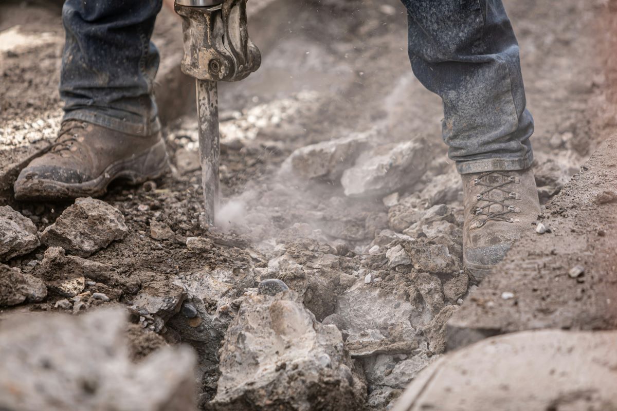 Man using a tool to drill into rocks and dirt