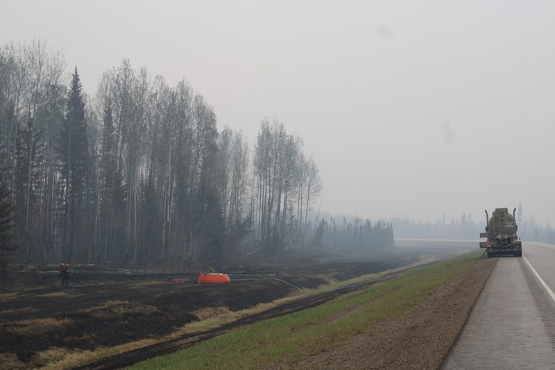 The mayor of the regional municipality that includes the evacuated community of Fort Nelson, B.C., says local officials are pushing for a Monday or Tuesday deadline to start allowing about 4,700 residents home after nearly two weeks. Firefighters working the Parker Lake wildfire, designated G90267 by the B.C. Wildfire Service, are seen in a staging area along Highway 97 looking south with a water bladder and fire hose set up among charred grassland in a May 15, 2024, handout photo. THE CANADIAN PRESS/HO-BC Wildfire Service,