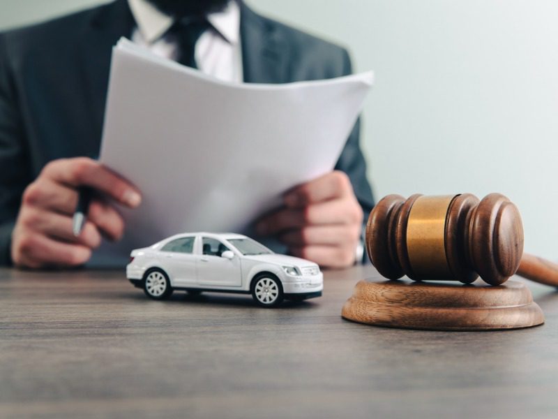 Legal judge with toy car and gavel on table