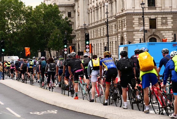 Cyclists wait in line on a cycle path for the lights to change