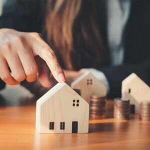 Miniature wooden houses with a stack of coins