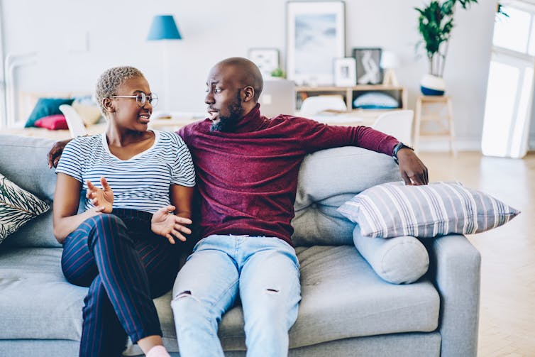 A couple talking on a couch.