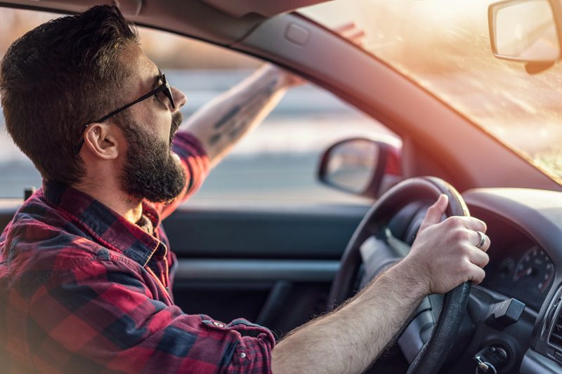 Angry young man gesturing and shouting at other drivers on the road.