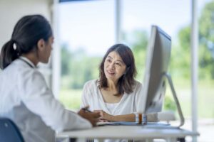 A woman talks to a physician about menopause symptoms in an office.