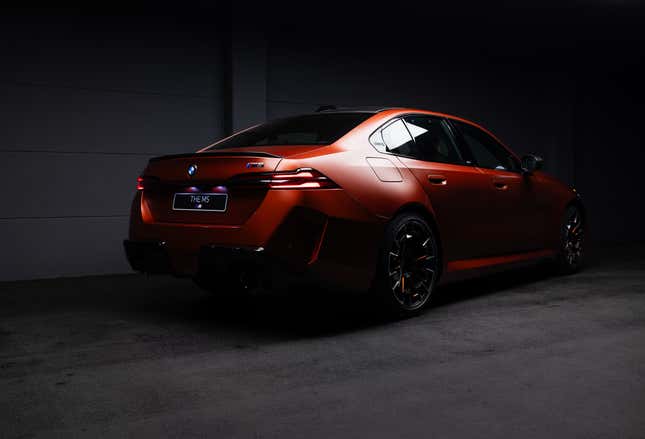 Rear 3/4 view of a matte orange 2025 BMW M5