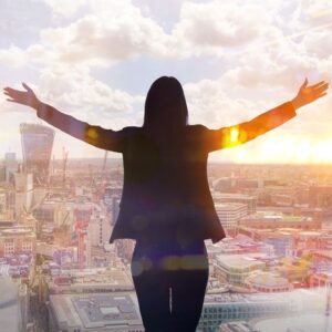 Woman looking out window with arms up, symbolizing success and positive outlook