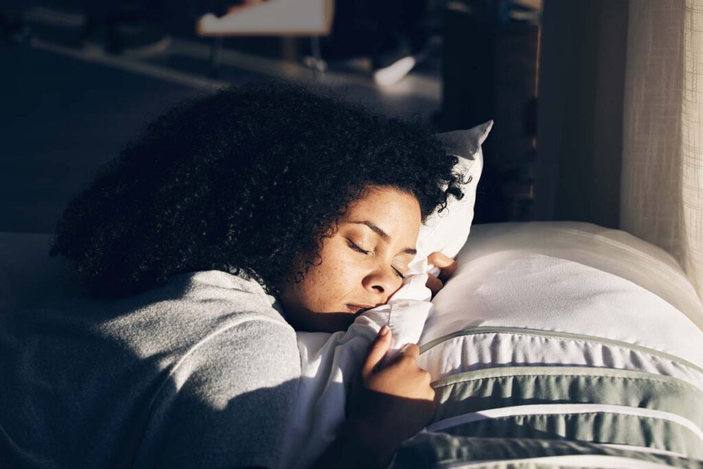 A woman sleeps on her side, holding her pillow.