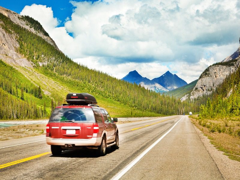 Red SUV auto mobile driving through Canadian Rockies in Banff National Park, Alberta, Canada