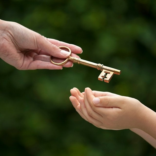 Hand passing key to child