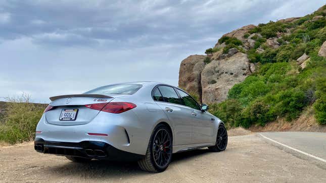 Another rear 3/4 shot of the silver C63 parked in front of a giant rock 