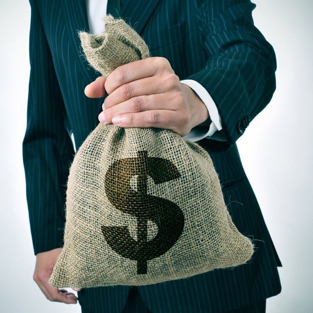 a businessman holding a burlap money bag