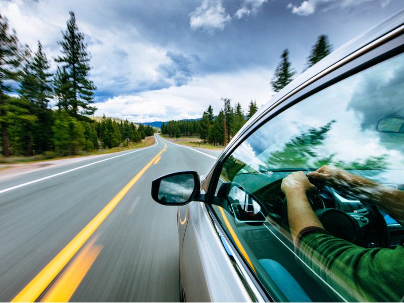 Electric vehicle driving down tree-lined road