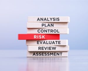 Risk management related words written wood blocks sitting on a wood surface in front of a defocused background. Risk management concept.