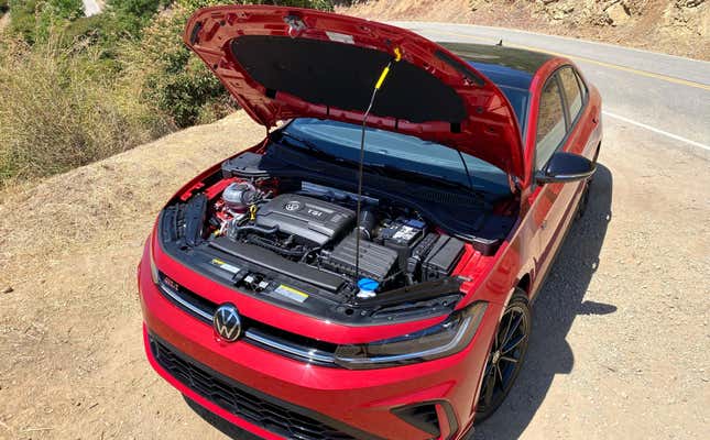 A photo of the red Jetta GLI parked on dirt with the hood up showing the engine