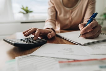 Person writing on a desk and using a calculator.