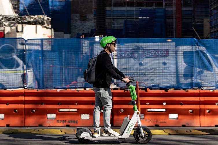 A person rides a Lime e-scooter through the city