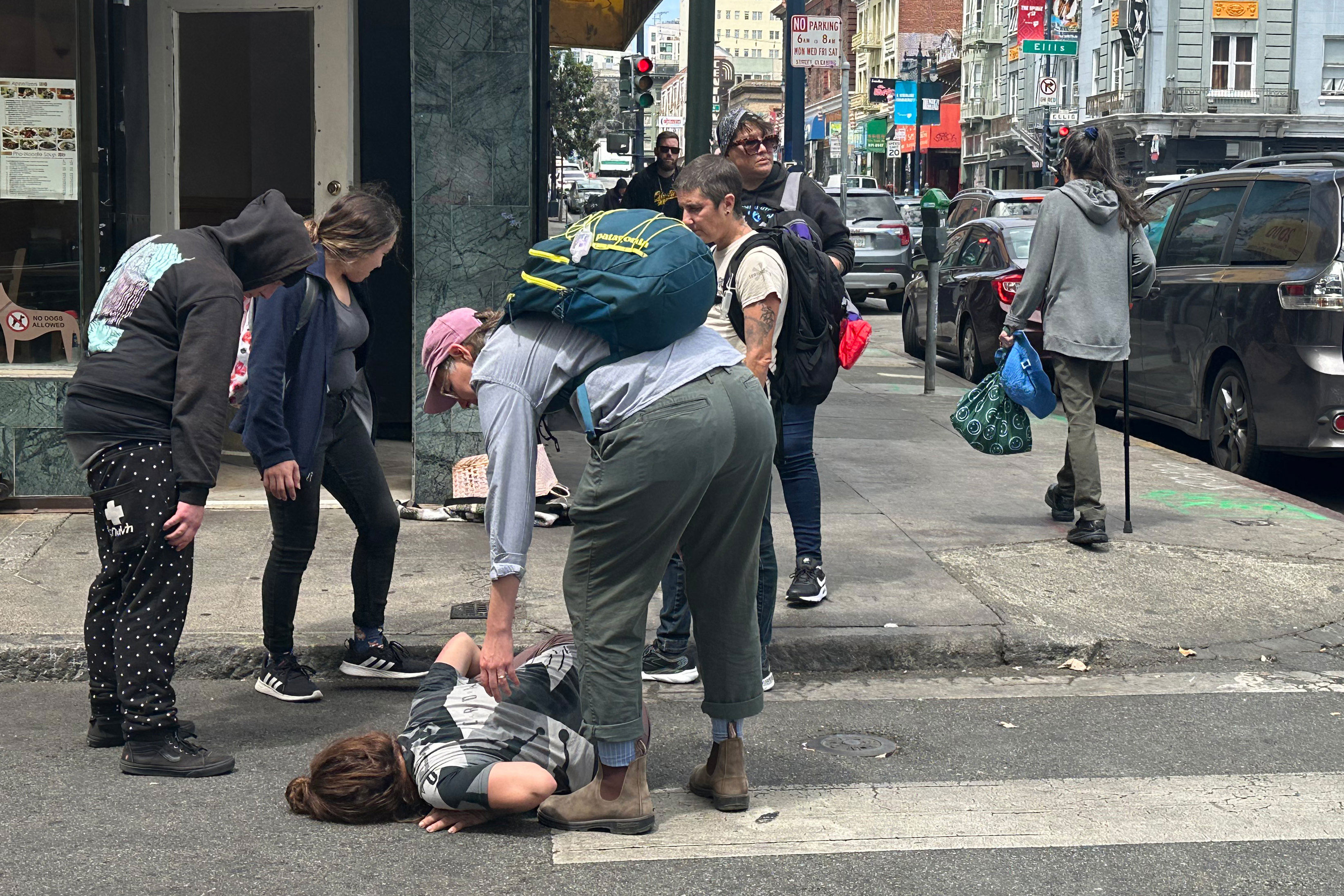 A photo of a street medic tending to a woman lying on the street.