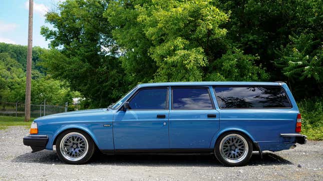 A side view of the volvo wagon in front of trees