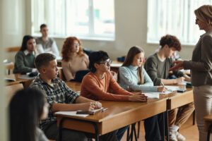 Large group of high school students listening to their teacher on a class in the classroom.