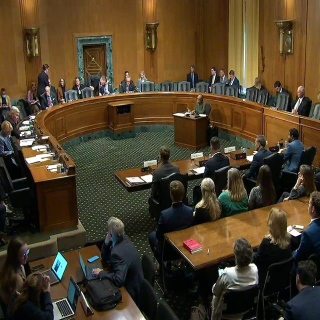 A committee hearing room full of senators, witnesses and others