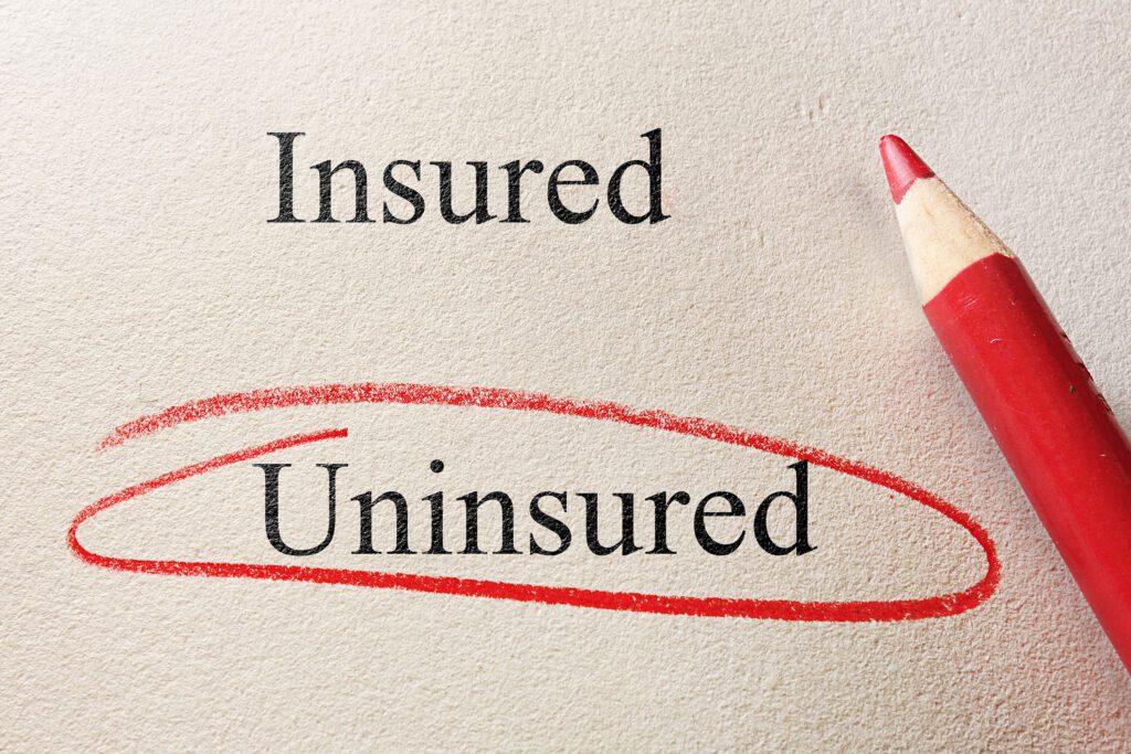 A photo of a piece of paper with the words "insured" and "uninsured" on it. "Uninsured" is circled with a red colored pencil.