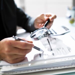 A man with a magnifying glass and documents.