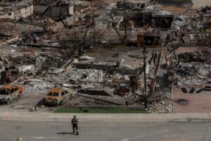 A worker walks through a devastated neighbourhood in west Jasper, Alta.